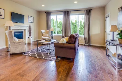 Living room with a dark hardwood floor, a white fireplace and tall windows